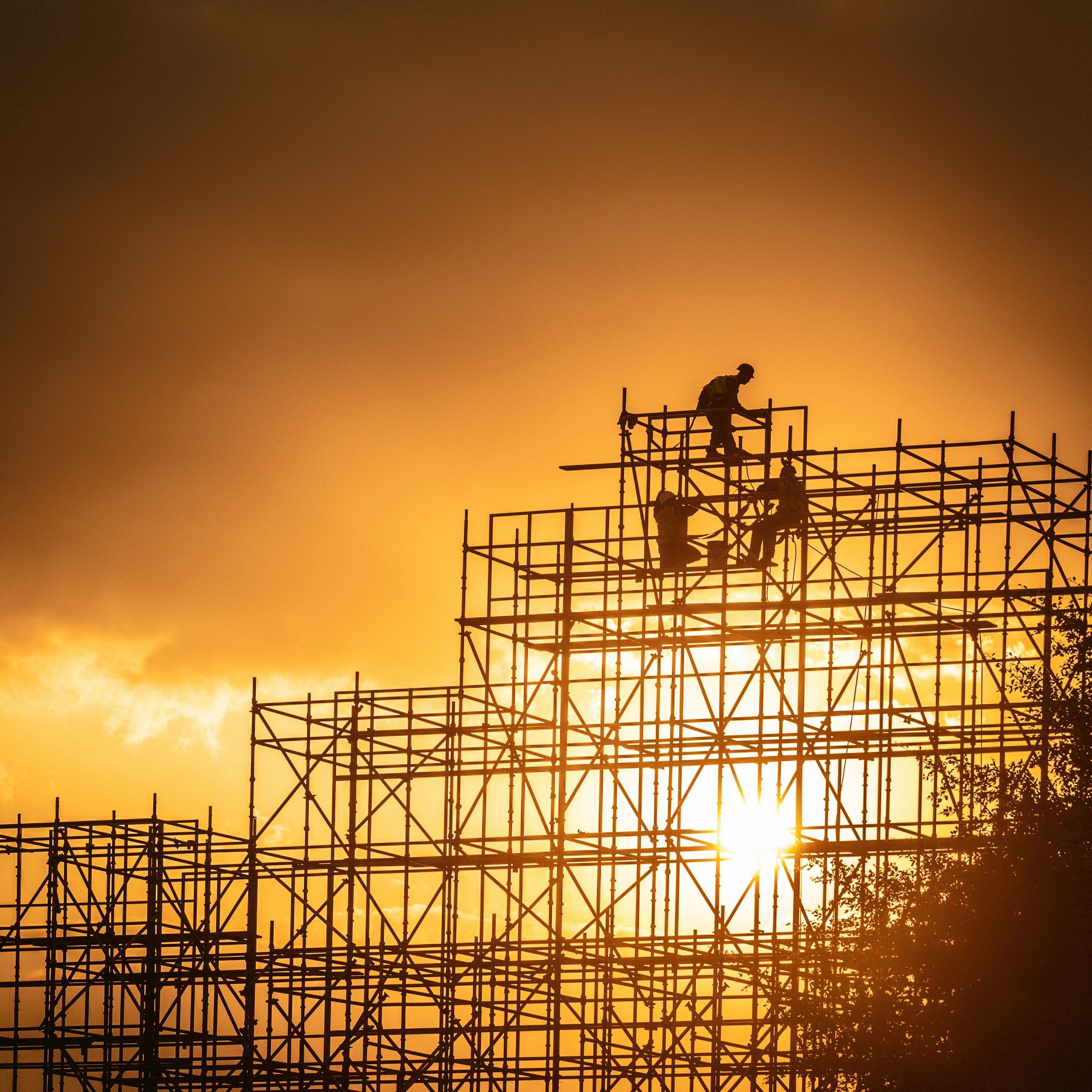 Trabajadores en andamios al atardecer dorado